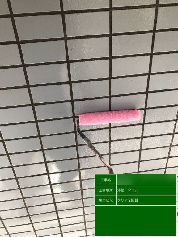 Fマンションの白系外壁タイルへピンク色のローラーでクリア塗装2回目を施工