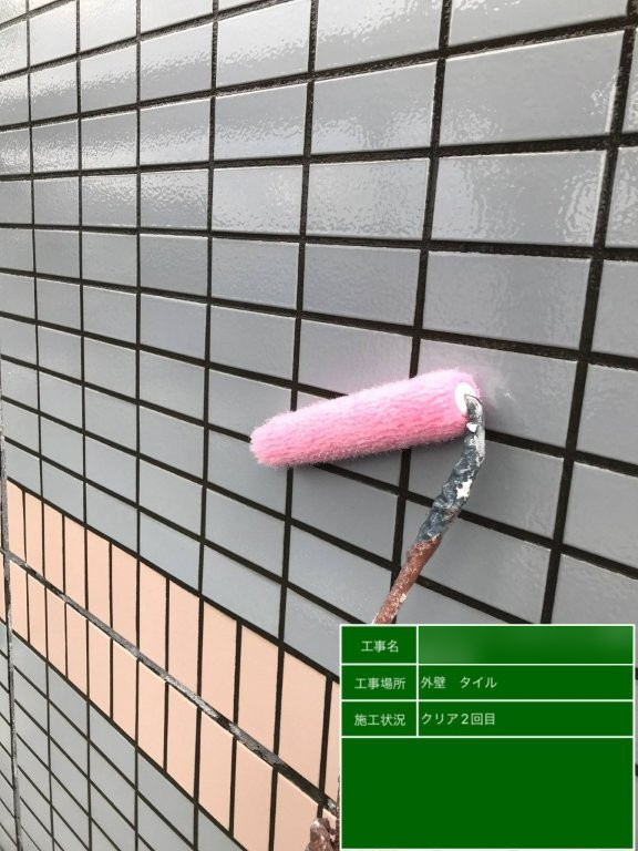 Fマンション グレー系外壁タイルにローラーでクリア塗装2回目を施工している様子